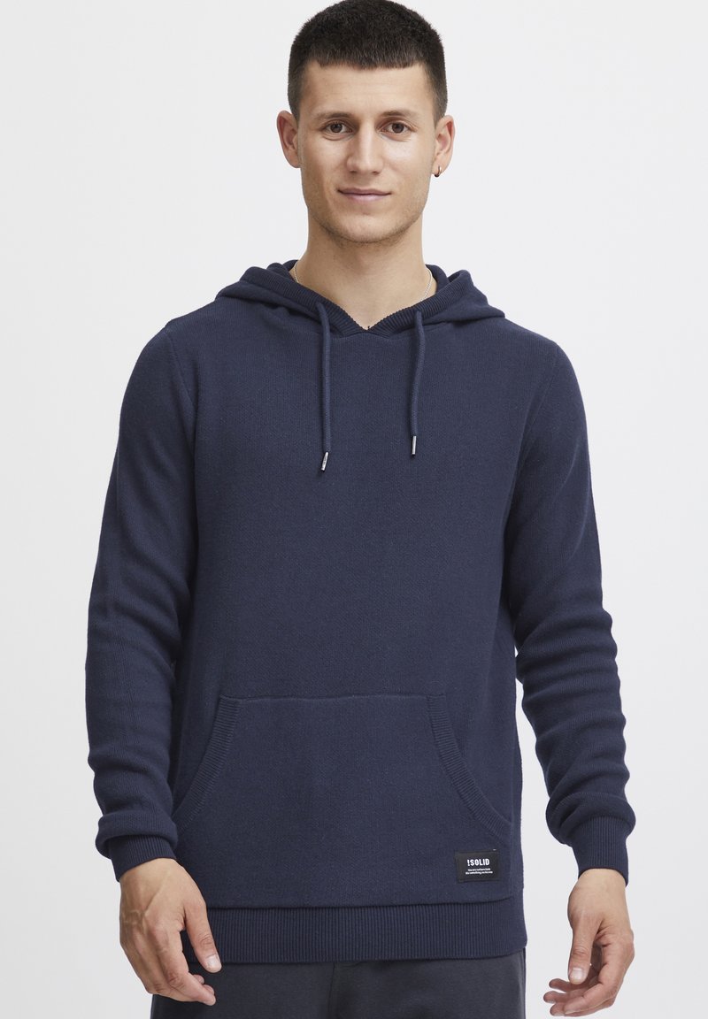 Sudadera azul marino de tejido suave con bolsillo canguro frontal, cordones ajustables y puños y dobladillo acanalados. Diseño liso.