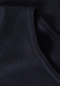 Tissu tricoté bleu marine foncé avec un bord en V côtelé, montrant la texture et les détails de plis doux.