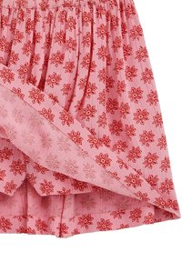 Roosa volditud seelik punase lillemustriga ja volditud äärega detail.