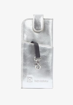 Borsa per telefono in metallo argentato con chiusura a scatto, tasca frontale e una tracolla nera con clip. Superficie testurizzata con branding in rilievo.