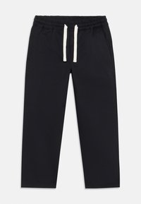 Pantalons de jogging noirs avec une taille élastique, des cordons blancs, des poches latérales et une texture de tissu lisse. Design à longueur raccourcie.
