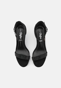 Sandali con tacco alto in suede nero con un cinturino luccicante che attraversa le dita dei piedi, fibbia regolabile alla caviglia e rivestimento interno morbido.