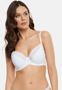 Weißer Unterwäsche-BH aus glattem Stoff mit zartem Spitzenbesatz an den Cups und einem kleinen Schleifen-Detail in der Mitte. Verstellbare Träger.