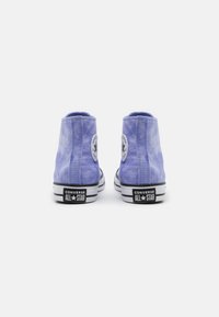 Un paio di sneaker alte Converse All Star di colore viola chiaro viste da dietro, su uno sfondo bianco.
