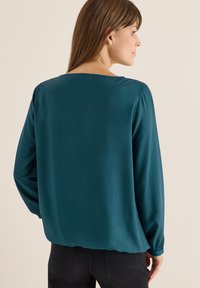 Türkisfarbige Bluse mit einer glatten, seidigen Textur, langen Ärmeln und einem quadratischen Ausschnitt. Verfügt über geraffte Manschetten und einen lockeren, entspannten Schnitt.