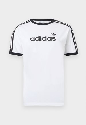Fehér pamutpóló fekete részletekkel, kerek nyakkal, rövid ujjal, a vállakon három fekete csíkkal és fekete "adidas" logóval.