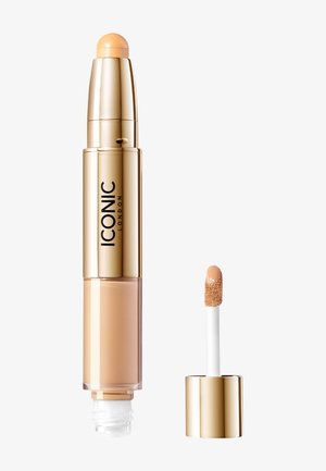 Beige concealer-stift med en rund applikator-spids, guldomslag og en separat doe-foot applikator i en guld- og hvid beholder.