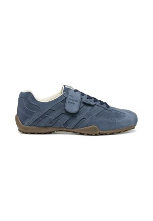 Zapatilla deportiva de ante azul oscuro con suela de goma marrón, cordones delanteros y una etiqueta de marca que dice The Original Snake en el lado.