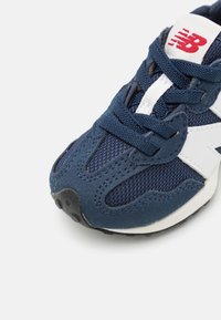 Navy blue athletic shoe featuring mesh and suede materials, white accents, round toe, flat rubber sole, and classic lace-up design.