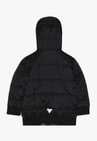 Chaqueta de plumas negra con capucha, con costuras horizontales, puños elásticos y un acento de logo triangular en el dobladillo. Textura suave.