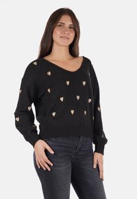 Maglione nero con scollo a V, caratterizzato da motivi a cuore dorati, vestibilità ampia e maniche lunghe. Realizzato in un morbido tessuto testurizzato.