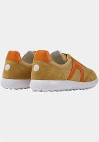 Zapatillas deportivas con parte superior de ante beige, detalles en cuero naranja y una suela blanca con fondo texturizado para mayor agarre.