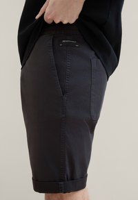 Ciemnonawiwowe szorty wykonane z lekkiego materiału. Posiadają zrolowany brzeg, boczne kieszenie oraz metkę z logo na tylnym pasku.