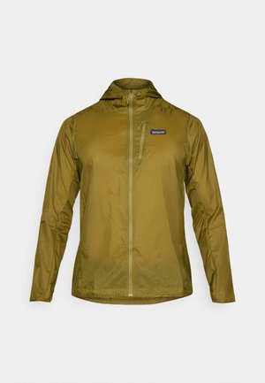 Olīvzaļš viegls jaciņš ar kapuci, pilna garuma rāvējslēdzis un neliela kabata krūtīs ar rāvējslēdzēju. Strukturēta auduma ar maigu spīdumu.