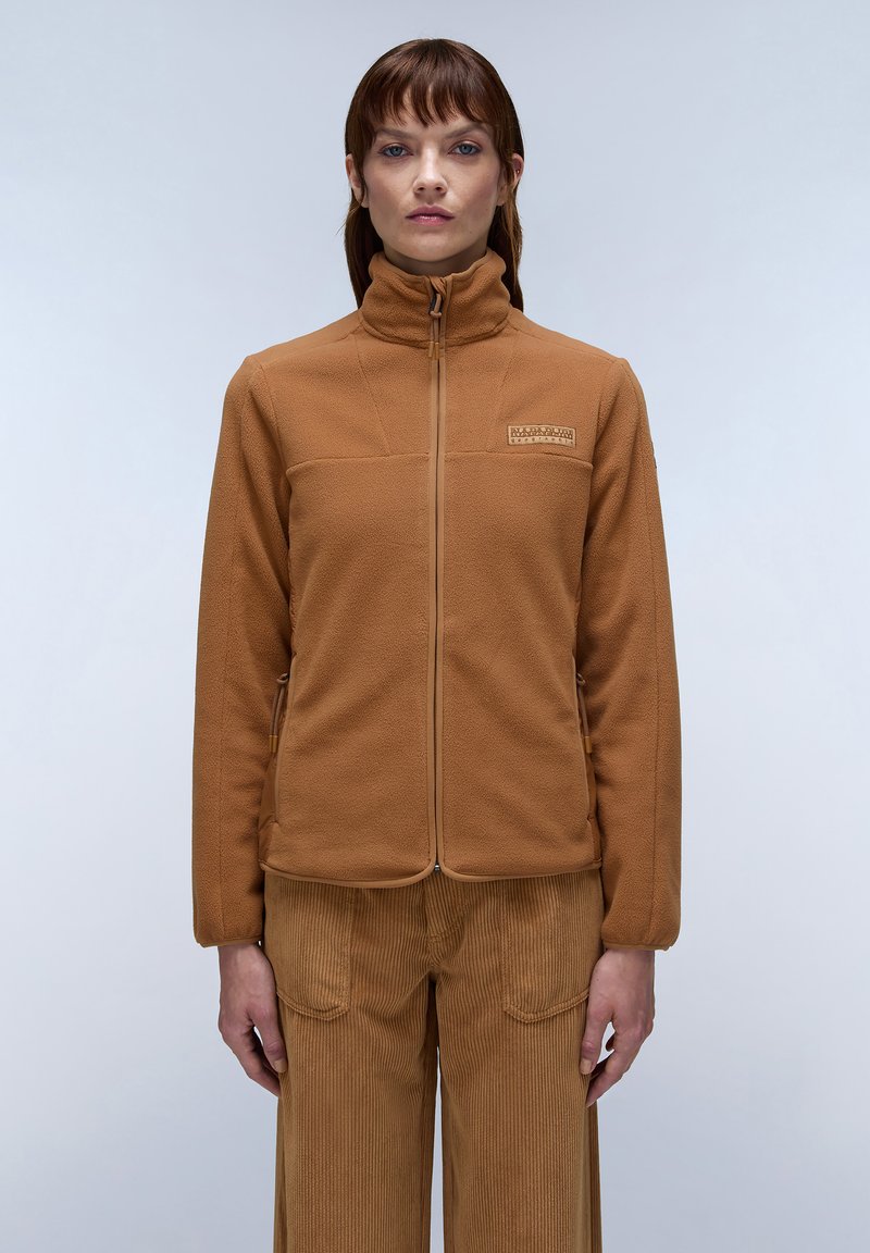 Giacca in pile marrone con collo alto e zip frontale; presenta un logo discreto sul petto e un tessuto strutturato; abbinata a pantaloni in velluto a coste coordinati.