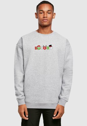 Grå sweatshirt med et farverigt "HO HO HO" grafik, der inkluderer en julesvamp, rensdyrhorn og en snemandshat. Løs pasform og ribbede manchetter.