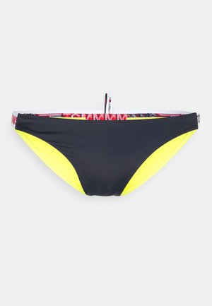 Parte de baixo de biquíni preta com painéis laterais em amarelo neon, apresentando uma cintura com detalhes em logotipo vermelho e branco e um pequeno laço na parte de trás.