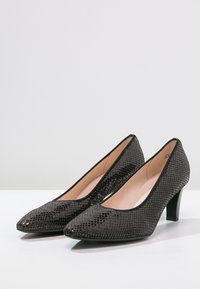 Escarpins en cuir verni noir avec un motif reptilien texturé, à bouts pointus et à talon bloc de hauteur intermédiaire. L'intérieur est d'une teinte beige lisse.