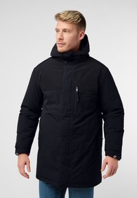 Giacca nera isolata con cappuccio, dotata di tasca sul petto con zip, bottoni a pressione e una superficie esterna liscia. Design a vestibilità casual.