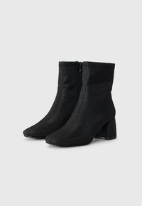 Black ankle boots with a textured, shimmering finish. Pointed toe and mid-height block heel. Features a side zipper for easy wear.