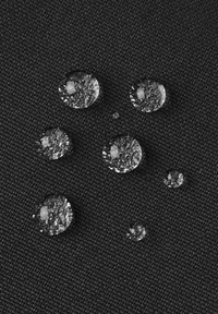Wassertropfen auf einer strukturierten schwarzen Stoffoberfläche, unterschiedlich groß, reflektieren Licht mit klaren Formen und Kanten.