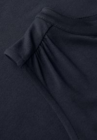 Granatowa koszulka z okrągłym dekoltem, z miękką teksturą i marszczeniami na szwie ramienia.