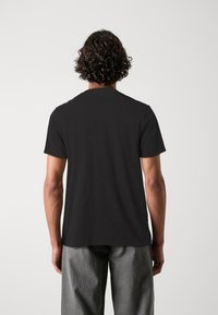 Camiseta negra de manga corta con cuello redondo, hecha de suave tela de algodón. Presenta un diseño sencillo sin gráficos ni logotipos visibles.