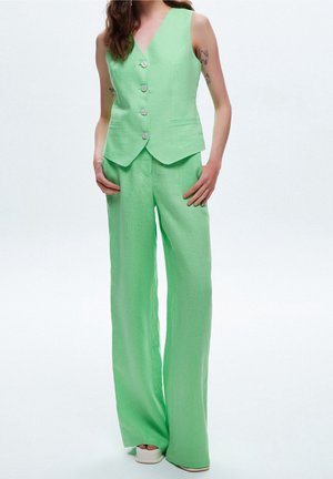 Groene linnen vest met vijf knopen en een notch-lapel, gecombineerd met wijde broekspijpen. Gladde textuur, lichte stof, zonder patronen of accenten.