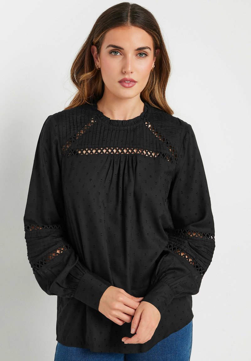 Blusa nera a maniche lunghe con tessuto texturizzato, dettagli plissettati, inserti in pizzo sulle spalle e scollatura rotonda.