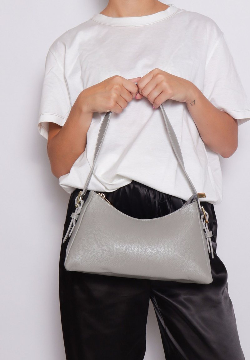 Borsa a tracolla in pelle grigia chiara con forma curvata, caratterizzata da una texture sottile, tracolla regolabile e dettagli in metallo dorato.