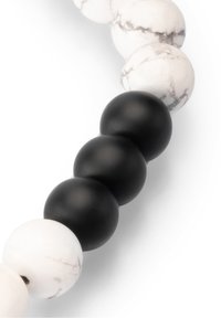 Black and white bead necklace featuring smooth black matte spheres and marbled white spheres with gray veining, arranged alternately.