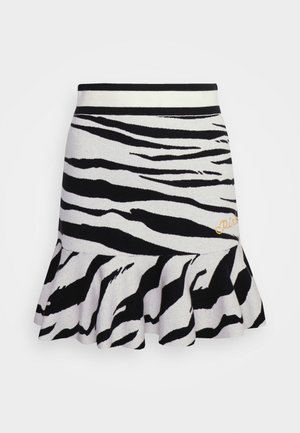 Jupe en tricot avec un motif zèbre noir et blanc, taille élastique et ourlet volanté évasé, avec "Pink" brodé en doré.