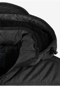 Innenansicht einer schwarzen Jacke mit weichem, dunklem Sherpa-Futter, glattem Stoff, elastischen Bündchen und einem Reißverschluss mit Zipper.