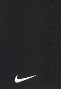 Czarne spodenki sportowe wykonane z gładkiego, elastycznego materiału, z białym logo Nike w prawym dolnym rogu oraz widocznymi szwami wzdłuż krawędzi.