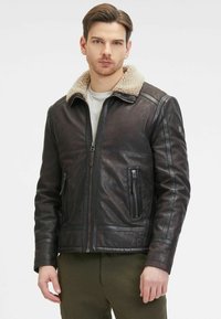 Giubbotto in pelle marrone con colletto in shearling beige, chiusura a zip, due tasche frontali con zip e dettagli di cucitura orizzontale sulle maniche.
