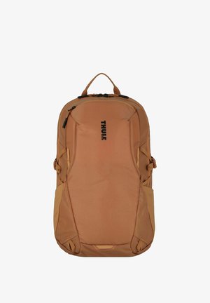 Zaino Thule in tessuto beige con una texture liscia, dotato di chiusura con zip, cinturini laterali regolabili e maniglia superiore per il trasporto.