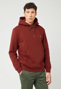 Bordeauxkleurige hoodie met een trekkoordkap, een voorzak en een klein logo op de linkerkant van de borst. Gemaakt van zachte, gestructureerde stof.