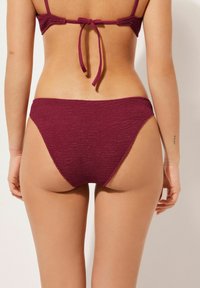 Burgunderfarbene, strukturierte Bikiniunterteile mit hohem Schnitt und weichem Bund, ausgestattet mit einem glatten Finish und einem minimalen Bedeckungsdesign.