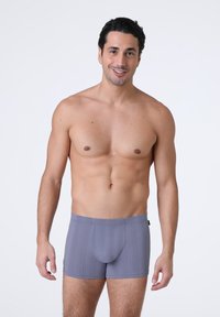 Boxer da uomo grigi con una texture a coste, caratterizzati da un design aderente e una vita senza cuciture. Nessun marchio o motivo visibile.