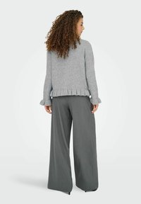 Pull en tricot gris avec une bordure et des poignets à volants, associé à un pantalon large gris. Texture douce et coupe décontractée, vu de l'arrière.