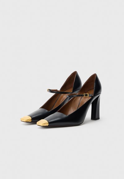 Pantofi cu toc înalt din piele neagră, cu vârf pătrat și accente aurii, având o curea decorativă și toc bloc pentru stabilitate.