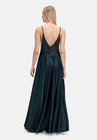 Robe de soirée longue en bleu sarcelle foncé avec une jupe en satin, un corsage en dentelle perlé et un dos en V. Bretelles réglables et silhouette fluide.