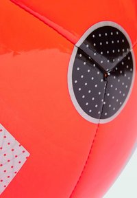 Pallone da calcio rotondo con una superficie arancione vivace, accenti neri, finitura lucida e punti bianchi; le cuciture sono visibili lungo il design.