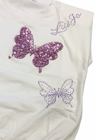Top bianco con due design di farfalle in paillettes viola, una grande con decorazioni scintillanti e un'altra più piccola con accenti decorativi.