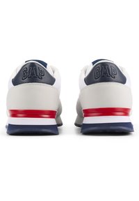Texturierte graue und weiße Sneaker mit einem navyblauen Absatz, roten Akzenten und einem auffälligen GAP-Logo auf der Rückseite. Gummisohle mit mehrfarbigen Schichten.