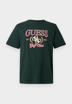 Roheline puuvillane t-särk, millel on uhked punased tähed "GUESS", brodeeritud logoelemendid ja tekst "Golf Club". Lühikesed varrukad ja ümar kaelus.