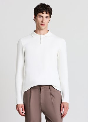 Weißes langärmliges Polo-Shirt mit Kragen, das ein strukturiertes Strickdesign aufweist, kombiniert mit braunen maßgeschneiderten Hosen.