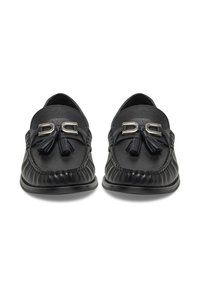 Melnas ādas mokasīnas ar teksturētu virsmu, sudraba aksesuāriem un dekoratīvu pušķi. Plakans zole un klasika dizains.