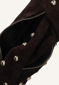 Bruine suède handtas met een ritssluiting, voorzien van zilveren studaccenten en een gestructureerde binnenkant. Het interieur is gevoerd en ruim.