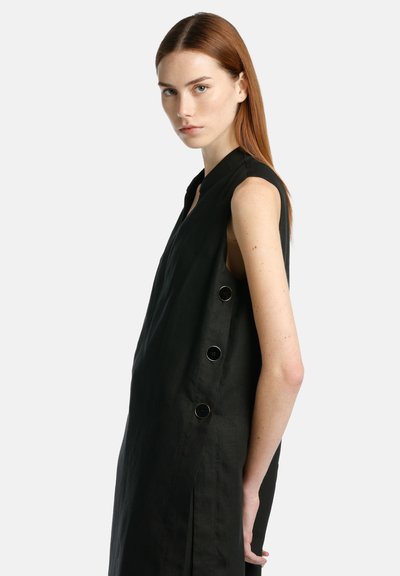 Black sleeveless dress with a high collar, side slits, and five large black buttons on the left side. Made from a textured fabric.